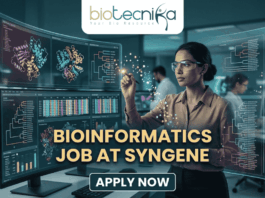Dream Bioinformatics Job at Syngene | Associate Scientist Role You Can’t Miss! A high-tech promotional graphic for a Bioinformatics Job at Syngene, featuring the Biotecnika logo at the top. The image depicts a female scientist in a professional office setting, using a digital stylus to interact with glowing, transparent holographic screens. These displays show complex biological data, including 3D molecular protein structures, genetic heatmaps, and phylogenetic trees. In the background, a modern laboratory with other researchers is visible. The central text reads "BIOINFORMATICS JOB AT SYNGENE" in bold gold lettering, with a dark blue "APPLY NOW" button located at the bottom center.