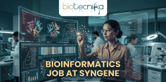 Dream Bioinformatics Job at Syngene | Associate Scientist Role You Can’t Miss! A high-tech promotional graphic for a Bioinformatics Job at Syngene, featuring the Biotecnika logo at the top. The image depicts a female scientist in a professional office setting, using a digital stylus to interact with glowing, transparent holographic screens. These displays show complex biological data, including 3D molecular protein structures, genetic heatmaps, and phylogenetic trees. In the background, a modern laboratory with other researchers is visible. The central text reads "BIOINFORMATICS JOB AT SYNGENE" in bold gold lettering, with a dark blue "APPLY NOW" button located at the bottom center.