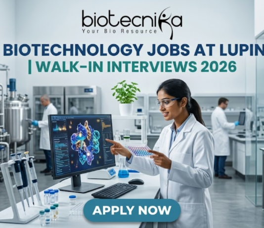 Lupin Walk-In Interviews 2026 | Biotechnology Jobs in R&D, Manufacturing & Quality Biotechnology Jobs at Lupin | Walk-In Interviews 2026. A high-quality, 1280x720 featured image for "Biotechnology Jobs at Lupin | Walk-In Interviews 2026." The image features the Biotecnika logo at the top center. In a modern, bright industrial laboratory, a female scientist in a white lab coat and safety goggles points to a monitor displaying a detailed 3D protein structure. Large stainless steel bioreactors and advanced lab equipment are visible in the background, creating a realistic pharmaceutical R&D atmosphere. The main title is displayed in bold teal and dark blue lettering, and a prominent blue "APPLY NOW" button is positioned at the bottom.