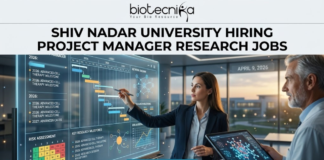 Research Jobs At Shiv Nadar University | Earn Upto ₹42,000/Month | Apply Now! Research Jobs at Shiv Nadar University | Apply Now. A high-quality, realistic featured image for a "Project Manager Research Jobs" opening at Shiv Nadar University. The scene features a professional woman in business attire interacting with a large, glowing transparent digital dashboard that displays research project timelines (Gantt charts), risk assessment matrices, and milestones for "Advanced Cell Therapy." A senior male colleague stands nearby holding a tablet with a 3D molecular visualization. The setting is a sleek, modern office with large windows overlooking a university campus at sunset. The Biotecnika logo is at the top, the main job title is in bold black text, and a prominent blue "Apply Now" button is at the bottom.