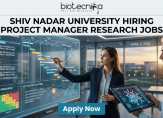 Research Jobs at Shiv Nadar University | Apply Now. A high-quality, realistic featured image for a "Project Manager Research Jobs" opening at Shiv Nadar University. The scene features a professional woman in business attire interacting with a large, glowing transparent digital dashboard that displays research project timelines (Gantt charts), risk assessment matrices, and milestones for "Advanced Cell Therapy." A senior male colleague stands nearby holding a tablet with a 3D molecular visualization. The setting is a sleek, modern office with large windows overlooking a university campus at sunset. The Biotecnika logo is at the top, the main job title is in bold black text, and a prominent blue "Apply Now" button is at the bottom.