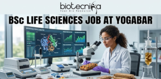 Freshers Wanted! BSc Life Sciences Job at Yogabar | Apply Now BSc Life Sciences Job at Yogabar Careers | Apply Now. A high-quality, professional featured image for a "BSc Life Sciences Job at Yogabar." The scene depicts a female food scientist in a white lab coat and safety goggles in a bright, modern food science laboratory. She is carefully examining a healthy snack bar under a professional microscope. On her desk are raw ingredients like chia seeds, flax seeds, and berries, alongside advanced lab equipment like a moisture analyzer. A large computer monitor in the background displays complex "Nutritional Profile Analysis" and 3D protein structures. The Biotecnika logo is at the top, the main job title is in bold black text, and a prominent "APPLY NOW" button is at the bottom.