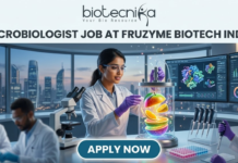 Fruzyme Biotech India Hiring Microbiologist Job | Freshers Eligible Apply Now! Microbiologist Job at Fruzyme Biotech India | Freshers Eligible. A professional and vibrant featured image for a "Microbiologist Job at Fruzyme Biotech India." The image depicts a female scientist in a high-tech lab working with a unique bioreactor containing glowing, levitating fruit slices, symbolizing specialized enzyme research. Modern lab equipment, data-filled monitors showing "Fruit Polysaccharide Enzyme Pathways," and a city skyline are visible in the background. The Biotecnika logo is positioned at the top center, the main title is in bold black text, and a prominent "APPLY NOW" button is at the bottom.