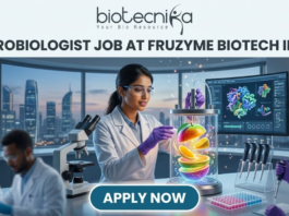 Fruzyme Biotech India Hiring Microbiologist Job | Freshers Eligible Apply Now! Microbiologist Job at Fruzyme Biotech India | Freshers Eligible. A professional and vibrant featured image for a "Microbiologist Job at Fruzyme Biotech India." The image depicts a female scientist in a high-tech lab working with a unique bioreactor containing glowing, levitating fruit slices, symbolizing specialized enzyme research. Modern lab equipment, data-filled monitors showing "Fruit Polysaccharide Enzyme Pathways," and a city skyline are visible in the background. The Biotecnika logo is positioned at the top center, the main title is in bold black text, and a prominent "APPLY NOW" button is at the bottom.