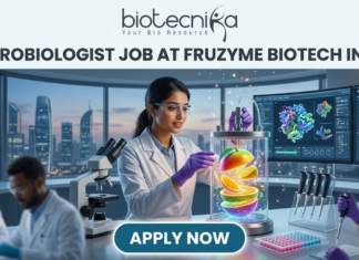 Microbiologist Job at Fruzyme Biotech India | Freshers Eligible. A professional and vibrant featured image for a "Microbiologist Job at Fruzyme Biotech India." The image depicts a female scientist in a high-tech lab working with a unique bioreactor containing glowing, levitating fruit slices, symbolizing specialized enzyme research. Modern lab equipment, data-filled monitors showing "Fruit Polysaccharide Enzyme Pathways," and a city skyline are visible in the background. The Biotecnika logo is positioned at the top center, the main title is in bold black text, and a prominent "APPLY NOW" button is at the bottom.