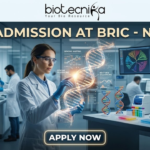 PhD Admission At BRIC - NIBMG | Fully Funded Research. A sleek, high-tech professional featured image for "PhD Admission At BRIC - NIBMG." The image features a focused female researcher in a white lab coat and safety glasses, interacting with a glowing, holographic 3D DNA helix in a modern genomic laboratory. The background shows other scientists working with advanced sequencing equipment and large curved monitors displaying genomic mapping data. The Biotecnika logo is at the top center, the main title is in elegant gold and white lettering, and a glowing "APPLY NOW" button is positioned at the bottom.