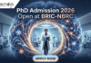 PhD Admission 2026 Open at BRIC-NBRC | Apply For Biotechnology & Neuroscience Program Today PhD Admission 2026 Open at BRIC-NBRC | Apply Online Today. A featured image for PhD Admission 2026 at BRIC-NBRC. The image shows a female scientist in a white lab coat standing in a futuristic laboratory, surrounded by a large, glowing holographic human brain with intricate neural pathways. The text "PhD Admission 2026 Open at BRIC-NBRC" is prominently displayed at the top center. The Biotecnika logo is in the top left corner, and a blue "APPLY NOW" button is positioned at the bottom. Background researchers work in a high-tech neurobiology research environment.
