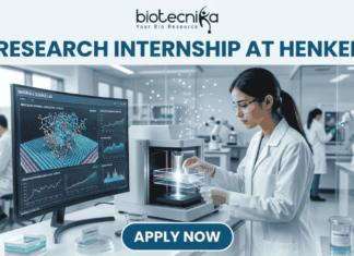 Research Internship at Henkel for MSc Biochemistry & Biotechnology Candidates | Apply Now! A professional featured image for a 'Research Internship at Henkel.' The visual shows a female scientist in a white lab coat and safety goggles working in a high-tech, modern laboratory. She is operating advanced analytical equipment while a large monitor in the background displays colorful 3D molecular simulations. The Biotecnika logo is placed at the top, and a prominent 'Apply Now' button is located at the bottom center.