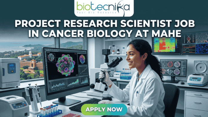 Project Research Scientist Job in Cancer Biology at MAHE Project Research Scientist Job in Cancer Biology at MAHE. A professional featured image for a job posting. At the center, a female scientist in a white lab coat smiles while working with a multi-channel pipette in a high-tech laboratory. Behind her, large computer monitors display vibrant 3D visualizations of cancer cells and molecular data. A window in the background offers a scenic view of a coastal campus. At the top center is the Biotecnika logo. Large, bold white text across the upper half reads: "PROJECT RESEARCH SCIENTIST JOB IN CANCER BIOLOGY AT MAHE". At the bottom center, there is a prominent, glowing green and blue "APPLY NOW" button.