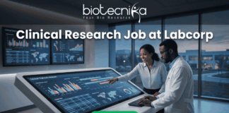 Clinical Research Job at Labcorp Bangalore | Apply Now! A realistic and attention-grabbing featured image, size 1280x720, designed for a job page. It features two black clinical researchers, a woman pointing and a man in a white lab coat, collaborating intensely at a massive, tilted touch-screen interface within a futuristic laboratory setting. The screen displays complex multi-colored data visualizations, timelines, maps, and charts with text labeling "Clinical Trial Data Analysis". Prominent white text at the top states: "Clinical Research Job at Labcorp". The complete Biotecnika logo (including text and tagline 'Your Bio Resource') is at the top-center. A distinct vibrant green "Apply Now" button is clearly positioned at the bottom-center.