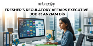 Fresher Regulatory Affairs Executive Job at ANZIAM Bio Apply. A recruitment poster for a "Fresher’s Regulatory Affairs Executive Job at ANZIAM Bio," featuring a young professional woman concentrating on a large computer monitor in a modern open-plan office with a cityscape view through the windows. The logo "biotecnika Global tagling technolgies" is at the top. On her desk, colorful files with labels like "Global Reg Guidelines," "EU Submission," and "ANZ Submission Protocols" are stacked, along with two globes. The computer screen shows regulatory pathways and charts. At the bottom center, a prominent green button reads "APPLY NOW".