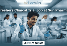Clinical Trial Job Alert: Freshers Wanted at Sun Pharma – Start Your Clinical Research Career Today! Freshers Clinical Trial Job at Sun Pharma | Don't Miss It. A featured image for a job posting titled "Freshers Clinical Trial Job at Sun Pharma" in a $1280 \times 720$ format.The image depicts a modern, high-tech laboratory setting where a young, smiling male scientist in a white lab coat is working with a pipette and a multi-well plate. A transparent digital holographic display in front of him shows "Clinical Trial Data" with various charts and graphs. In the background, other researchers are visible in a clean, professional clinical environment.The Biotecnika logo is positioned clearly at the top center, and a prominent, rounded "APPLY NOW" button is located at the bottom center. The overall aesthetic is professional, bright, and engaging.