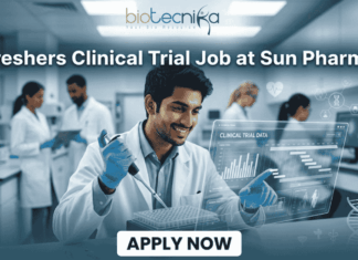 Clinical Trial Job Alert: Freshers Wanted at Sun Pharma – Start Your Clinical Research Career Today! Freshers Clinical Trial Job at Sun Pharma | Don't Miss It. A featured image for a job posting titled "Freshers Clinical Trial Job at Sun Pharma" in a $1280 \times 720$ format.The image depicts a modern, high-tech laboratory setting where a young, smiling male scientist in a white lab coat is working with a pipette and a multi-well plate. A transparent digital holographic display in front of him shows "Clinical Trial Data" with various charts and graphs. In the background, other researchers are visible in a clean, professional clinical environment.The Biotecnika logo is positioned clearly at the top center, and a prominent, rounded "APPLY NOW" button is located at the bottom center. The overall aesthetic is professional, bright, and engaging.