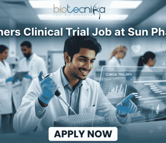 Freshers Clinical Trial Job at Sun Pharma | Don't Miss It. A featured image for a job posting titled "Freshers Clinical Trial Job at Sun Pharma" in a $1280 \times 720$ format.The image depicts a modern, high-tech laboratory setting where a young, smiling male scientist in a white lab coat is working with a pipette and a multi-well plate. A transparent digital holographic display in front of him shows "Clinical Trial Data" with various charts and graphs. In the background, other researchers are visible in a clean, professional clinical environment.The Biotecnika logo is positioned clearly at the top center, and a prominent, rounded "APPLY NOW" button is located at the bottom center. The overall aesthetic is professional, bright, and engaging.