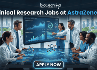Hiring Now! Clinical Research Jobs at AstraZeneca for Life Science Graduates! Hiring Now! Clinical Research Jobs at AstraZeneca for Life Science Graduates! A professional featured image for "Clinical Research Jobs at AstraZeneca." It shows a group of medical researchers in lab coats gathered around a large interactive touch-table displaying clinical trial data, graphs, and 3D molecular models. The Biotecnika logo is at the top, and a sleek "Apply Now" button is at the bottom.