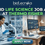 Hybrid Life Science Job Alert at Thermo Fisher. A professional split-screen featured image for a "Hybrid Life Science Job Alert at Thermo Fisher." The left side shows a female scientist in a white lab coat working in a high-tech laboratory with a centrifuge. The right side shows a professional woman working on a laptop at a modern desk, representing remote work. A glowing DNA double helix is centered between the two scenes. The Biotecnika logo is at the top, and a large "APPLY NOW" button is at the bottom center.