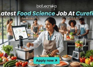 Latest Food Science Job At Curefit | Apply For Nutritionist Role Today! Latest Food Science Job At Curefit Apply For Nutritionist Role. A sleek, lifestyle-oriented featured image for "Latest Food Science Job At Curefit." It shows a food scientist in a modern culinary lab using smart kitchen technology like a sous-vide machine and a tablet dashboard. The Biotecnika logo is at the top, and a cyan "Apply now" button is at the bottom.