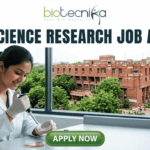 Life Science Research Job At Jawaharlal Nehru University (JNU). A high-quality featured image for a job page (1280x720) with the "biotecnika" logo and text at the top. Large, clear text reads: "MSc LIFE SCIENCE FRESHERS JOB at Thermo Fisher Scientific". Imagery shows a diverse group of four young scientists in lab coats and stylish casual wear collaborating enthusiastically around a transparent screen displaying a colourful 3D molecular model, within a sophisticated, sunlit laboratory. The background features unbranded lab equipment and natural light. A distinct green rectangular button at the bottom center has the text "Apply Now", with smaller text "MSc LIFE SCIENCE FRESHERS JOB" below it. The entire top section is framed by a deep teal textured banner. The scene is realistic, attractive, and conveys energy and discovery, suitable for going viral.