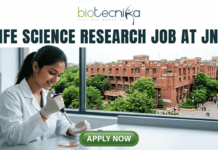 Life Science Research Job At Jawaharlal Nehru University (JNU) | Apply Now! Life Science Research Job At Jawaharlal Nehru University (JNU). A high-quality featured image for a job page (1280x720) with the "biotecnika" logo and text at the top. Large, clear text reads: "MSc LIFE SCIENCE FRESHERS JOB at Thermo Fisher Scientific". Imagery shows a diverse group of four young scientists in lab coats and stylish casual wear collaborating enthusiastically around a transparent screen displaying a colourful 3D molecular model, within a sophisticated, sunlit laboratory. The background features unbranded lab equipment and natural light. A distinct green rectangular button at the bottom center has the text "Apply Now", with smaller text "MSc LIFE SCIENCE FRESHERS JOB" below it. The entire top section is framed by a deep teal textured banner. The scene is realistic, attractive, and conveys energy and discovery, suitable for going viral.