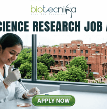 Life Science Research Job At Jawaharlal Nehru University (JNU) | Apply Now! Life Science Research Job At Jawaharlal Nehru University (JNU). A high-quality featured image for a job page (1280x720) with the "biotecnika" logo and text at the top. Large, clear text reads: "MSc LIFE SCIENCE FRESHERS JOB at Thermo Fisher Scientific". Imagery shows a diverse group of four young scientists in lab coats and stylish casual wear collaborating enthusiastically around a transparent screen displaying a colourful 3D molecular model, within a sophisticated, sunlit laboratory. The background features unbranded lab equipment and natural light. A distinct green rectangular button at the bottom center has the text "Apply Now", with smaller text "MSc LIFE SCIENCE FRESHERS JOB" below it. The entire top section is framed by a deep teal textured banner. The scene is realistic, attractive, and conveys energy and discovery, suitable for going viral.