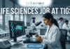 Life Sciences Job at TIGS Research Scientist & Support Roles. A professional featured image (1280x720) for a Life Sciences Job at TIGS. The scene depicts a modern, high-tech laboratory where a female scientist of South Asian descent is meticulously working with a microscope. To her left, a large computer monitor displays a glowing green digital 3D model of a mosquito overlaid with a DNA double helix, signifying genetic research. The Biotecnika logo is prominently placed at the top center. The text "LIFE SCIENCES JOB AT TIGS" is written in bold, white capital letters across the top. At the bottom center, there is a sleek, blue "APPLY NOW" button. The background shows a bright, clean research facility with other scientists in lab coats, creating an atmosphere of innovation and discovery.