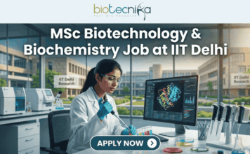 MSc Biotechnology & Biochemistry Job at IIT Delhi – Enzyme Assay Specialist Role Open Now! MSc Biotechnology & Biochemistry Job at IIT Delhi. A professional and realistic featured image for a job opening. At the top center is the Biotecnika Global logo, followed by large, bold text reading "MSc Biotechnology & Biochemistry Job at IIT Delhi." The central scene depicts a female researcher in a white lab coat working in a high-tech laboratory, using a pipette on colorful samples while viewing a 3D molecular structure on a large monitor. The background shows advanced lab equipment and a clear view of the IIT Delhi Research campus through large windows. At the bottom, there is a prominent teal button that says "APPLY NOW" with a white arrow icon.
