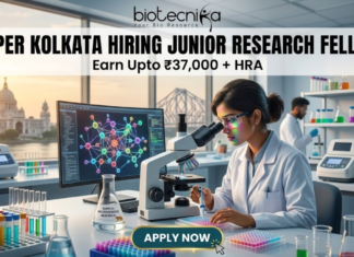 NIPER Kolkata Hiring Junior Research Fellow | Get Upto ₹37,000 + HRA | Apply Online Now!! NIPER Kolkata Hiring Junior Research Fellow. Alt Text: A high-quality, professional featured image for a "Junior Research Fellow" job opening at NIPER Kolkata. The scene features a focused female scientist in a white lab coat and safety glasses working in a futuristic laboratory. Through the large windows, iconic Kolkata landmarks like the Victoria Memorial and the Howrah Bridge are visible at sunset. The image includes the Biotecnika logo at the top center, the bold headline "NIPER KOLKATA HIRING JUNIOR RESEARCH FELLOW," and a tagline stating "Earn Upto ₹37,000 + HRA." A prominent "APPLY NOW" button is positioned at the bottom center.