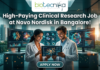 Novo Nordisk Hiring Clinical Data Scientist – High-Paying Clinical Research Job in Bangalore! A promotional featured image for a job opening, featuring the headline "High-Paying Clinical Research Job at Novo Nordisk in Bangalore!" in bold white text at the top. The Biotecnika logo is positioned at the top center. The central visual shows two professional researchers—a woman and a man in white lab coats—smiling and collaborating while looking at a digital tablet that displays a glowing neural network. They are standing in a futuristic, high-tech laboratory equipped with large, curved monitors showing 3D protein structures and complex biological data. Through the large glass windows behind them, a modern city skyline is visible during a warm sunset. At the bottom center, there is a prominent, stylized "APPLY NOW" button.