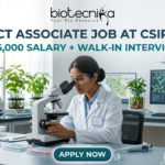 Project Associate Job at CSIR-NEERI | ₹35,000 Salary + Walk-in Interview | Don’t Miss! Project Associate Job at CSIR-NEERI ₹35,000 Salary + Walk-in Interview – Life Science Graduates Don’t Miss! A high-quality featured image for a "Project Associate Job at CSIR-NEERI." The image depicts a female scientist in a white lab coat and safety glasses, meticulously focused as she uses a microscope in a bright, modern environmental laboratory. The lab is filled with scientific equipment, soil samples in glass jars, and healthy green plants, reflecting an environmental research theme. A computer monitor in the background displays biological data and microscopic views of microbes. The Biotecnika logo is at the top, followed by the bold title and a tagline stating "₹35,000 SALARY + WALK-IN INTERVIEW." A prominent teal "APPLY NOW" button is located at the bottom center.