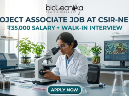 Project Associate Job at CSIR-NEERI ₹35,000 Salary + Walk-in Interview – Life Science Graduates Don’t Miss! A high-quality featured image for a "Project Associate Job at CSIR-NEERI." The image depicts a female scientist in a white lab coat and safety glasses, meticulously focused as she uses a microscope in a bright, modern environmental laboratory. The lab is filled with scientific equipment, soil samples in glass jars, and healthy green plants, reflecting an environmental research theme. A computer monitor in the background displays biological data and microscopic views of microbes. The Biotecnika logo is at the top, followed by the bold title and a tagline stating "₹35,000 SALARY + WALK-IN INTERVIEW." A prominent teal "APPLY NOW" button is located at the bottom center.