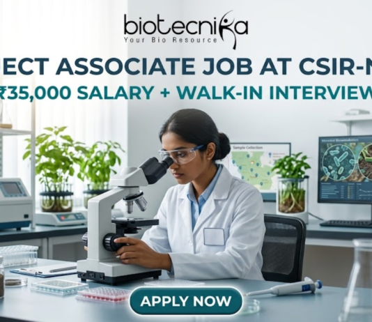 Project Associate Job at CSIR-NEERI ₹35,000 Salary + Walk-in Interview – Life Science Graduates Don’t Miss! A high-quality featured image for a "Project Associate Job at CSIR-NEERI." The image depicts a female scientist in a white lab coat and safety glasses, meticulously focused as she uses a microscope in a bright, modern environmental laboratory. The lab is filled with scientific equipment, soil samples in glass jars, and healthy green plants, reflecting an environmental research theme. A computer monitor in the background displays biological data and microscopic views of microbes. The Biotecnika logo is at the top, followed by the bold title and a tagline stating "₹35,000 SALARY + WALK-IN INTERVIEW." A prominent teal "APPLY NOW" button is located at the bottom center.