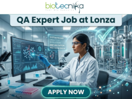 Limited Openings! QA Expert Job at Lonza Careers Hyderabad – Apply Fast! QA Job at Lonza Careers | QA Expert Hyderabad Role. A professional promotional image for a "QA Expert Job at Lonza" featuring the Biotecnika logo at the top. The scene depicts a female scientist in a white lab coat working in a state-of-the-art biotechnology facility. She is analyzing molecular data on a large computer monitor while a glowing holographic overlay displays a large green checkmark and text such as "GMP VALIDATION" and "SYSTEM PASSED." The background shows modern stainless steel bioreactors and laboratory equipment, emphasizing a high-standard Quality Assurance environment. A prominent teal "APPLY NOW" button is positioned at the bottom center.