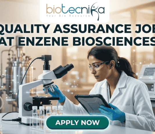 A professional promotional graphic for a Quality Assurance Job at Enzene Biosciences. At the top center is the Biotecnika Professional logo, followed by the headline "QUALITY ASSURANCE JOB AT ENZENE BIOSCIENCES" in bold, dark green lettering. The image features a female scientist in a white lab coat and safety glasses, focused on a digital tablet while working in a high-tech laboratory. The setting includes a microscope, rows of clear vials on a lab bench, and large-scale industrial bioreactors in the background. A glowing teal "APPLY NOW" button is positioned prominently at the bottom center.