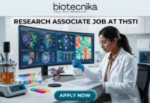 Research Associate Job at THSTI | PhD Life Sciences Candidates Earn Upto ₹47,000 Research Associate Job at THSTI PhD Life Sciences Candidates Earn Upto ₹47,000. A realistic, high-tech featured image for a "Research Associate Job at THSTI." At the top is the Biotecnika logo. The center features a female scientist in a white lab coat and safety glasses, meticulously using a pipette over a multi-well plate. Behind her, a large curved monitor displays complex molecular structures and colorful genomic data charts. The modern laboratory is filled with advanced scientific equipment like a bioreactor and centrifuge. At the bottom, there is a prominent teal "APPLY NOW" button.