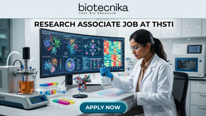 Research Associate Job at THSTI PhD Life Sciences Candidates Earn Upto ₹47,000 Research Associate Job at THSTI PhD Life Sciences Candidates Earn Upto ₹47,000. A realistic, high-tech featured image for a "Research Associate Job at THSTI." At the top is the Biotecnika logo. The center features a female scientist in a white lab coat and safety glasses, meticulously using a pipette over a multi-well plate. Behind her, a large curved monitor displays complex molecular structures and colorful genomic data charts. The modern laboratory is filled with advanced scientific equipment like a bioreactor and centrifuge. At the bottom, there is a prominent teal "APPLY NOW" button.