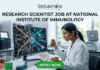 Research Scientist Job at National Institute of Immunology – Cancer Biology Project Hiring Now! "A featured image job banner titled 'RESEARCH SCIENTIST JOB AT NATIONAL INSTITUTE OF IMMUNOLOGY' and featuring the biotecnika 'IMMUNOLOG TECH' logo, depicting a focused Indian female scientist in a lab coat using a pipette while a complex, multi-colored 3D map of immune cell pathways is displayed on her curved monitor, with other high-tech lab equipment in the blurred background and a green 'APPLY NOW' button at the bottom."