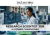 Research Scientist Job at PGIMER Chandigarh PhD in Life Sciences Candidates Apply Now. A 1280x720 image for a "Research Scientist Job at PGIMER Chandigarh." It features a smiling Indian female scientist in a lab, with the famous "Open Hand Monument" of Chandigarh visible through the window. The Biotecnika logo is at the top, the job title is centered on a white translucent bar, and a green "APPLY NOW" button is at the bottom.