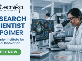 Research Scientist Vacancy at PGIMER Earn Upto ₹56,000. A featured image for a job page with a clean, professional layout. On the left side, against a light blue and white background, the Biotecnika logo is at the top, followed by the bold blue text "RESEARCH SCIENTIST at PGIMER" and a tagline "A Premier Institute for Medical Innovation." At the bottom left is a green "APPLY NOW" button. The right side of the image features a realistic, high-quality photo of a female scientist in a white lab coat and safety glasses working with a pipette in a modern laboratory. In the background, large computer monitors display vibrant, detailed microscopic imaging of cell structures.