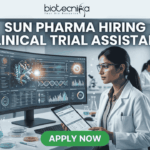 Sun Pharma Hiring Clinical Trial Assistant Apply Now. A professional and high-tech promotional image for a job opening. At the top, the Biotecnika logo is placed above the bold, capitalized headline: "SUN PHARMA HIRING CLINICAL TRIAL ASSISTANT". The central focus is a female scientist in a white lab coat and safety glasses, intently working at a desk. She is looking at a large, curved digital monitor that displays intricate clinical trial data, 3D molecular structures, and a glowing sun-like graphic representing the company theme. The laboratory setting is bright and modern, with other researchers working in the background and scientific equipment like pipettes and vials visible on the desk. At the bottom center, a vibrant green "APPLY NOW" button stands out, making the image an effective, scroll-stopping recruitment graphic.