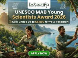 UNESCO MAB Young Scientists Award 2026 – Get Funded Up to $5,000 for Your Research! A featured job post image for the UNESCO MAB Young Scientists Award 2026. At the top center is the Biotecnika logo. The main text reads "UNESCO MAB Young Scientists Award 2026" with a sub-headline, "Get Funded Up to $5,000 for Your Research!" The background features a realistic and vibrant tropical coastal landscape with lush green mountains and turquoise water. Two scientists—a woman and a man in khaki field gear—are shown conducting environmental research; the woman uses a handheld probe and tablet while the man inspects a sensor device mounted on a tree. Drones fly in the background, emphasizing a high-tech conservation theme. At the bottom center is a prominent green "APPLY NOW" button.