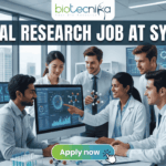 Urgent Hiring! Clinical Research Job at Syngene – Apply Today! A featured image for a job page, part of Biotecnika, showcasing a clinical research position at Syngene. At the top center is the Biotecnika logo, with the text 'Your Bio Resource'. The main bold title is 'CLINICAL RESEARCH JOB AT SYNGENE'. The background features a detailed, realistic photograph of a diverse team of five scientists and professionals (two women, three men) collaborating in a modern, well-equipped laboratory, looking collaboratively into a computer monitor showing data charts, graphs, and a detailed 3D molecular structure. The lab has advanced scientific instruments, beakers, and shelves, visible next to a large window. The overall scene conveys scientific innovation, teamwork, and professionalism. At the bottom center, there is a prominent orange rectangular button labeled 'Apply now'.