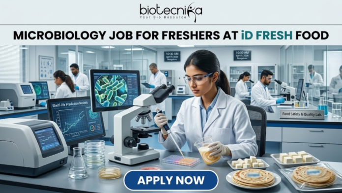 iD Fresh Food Hiring Quality Executive for Microbiology Job Freshers Eligible iD Fresh Food Hiring Quality Executive for Microbiology Job Freshers Eligible. A professional and high-quality featured image advertisement for a "Microbiology Job for Freshers at iD Fresh Food." The scene depicts a female scientist in a white lab coat and safety goggles working in a modern, high-tech Food Safety & Quality Lab. She is carefully testing food samples, such as idli/dosa batter and parottas, using a pipette and lab equipment. A computer monitor in the background shows detailed microbial cell structures. The Biotecnika logo is at the top center, the job title is displayed in bold black text, and a prominent blue "APPLY NOW" button is located at the bottom.