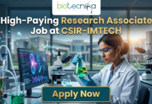 High-Paying Research Associate Job at CSIR-IMTECH – PhD Candidates Apply Now! Research Associate Job at CSIR-IMTECH | Apply Now. A high-quality promotional image for a "High-Paying Research Associate Job at CSIR-IMTECH" featuring the Biotecnika Global logo at the top center. The scene depicts a female scientist in a professional lab coat and safety goggles, carefully holding a flask filled with a glowing, bioluminescent green liquid. In the background, a modern laboratory is visible with a computer monitor displaying advanced microbial technology research, DNA structures, and molecular data. The lighting is a sleek, futuristic blue, and a prominent "Apply Now" button is positioned at the bottom center.