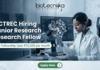 ACTREC Hiring Junior Research Fellow | Opportunity in Cancer Research ACTREC Hiring Junior Research Fellow Opportunity in Cancer Research. An advertisement for a Junior Research Fellow position at ACTREC, showing the Biotecnika logo at the top center. Text states: 'ACTREC Hiring Junior Research Fellow' and 'Get Fellowship Upto ₹35,000 per month'. A photograph on the right shows a female scientist in a lab coat, safety glasses, and blue gloves operating a multichannel pipette. Behind her, a monitor displays molecular drug discovery data. Various advanced lab instruments are in the background. At the bottom, a green 'Apply Now' button.
