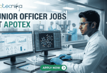 Apotex Hiring Junior Officers in Bangalore | Life Science Graduates Apply Now! Apotex Hiring Junior Officers in Bangalore Apply Now! A professional recruitment banner for "JUNIOR OFFICER JOBS AT APOTEX" featuring the Biotecnika logo at the top left. The image depicts a young male pharmaceutical professional in a white lab coat and blue gloves, meticulously monitoring data on dual computer screens. One screen displays analytical charts and graphs, while the other shows a 3D molecular structure. In the background, a sterile pharmaceutical production line with stainless steel machinery is visible through a large glass partition. On the right side, vertical teal icons highlight key roles: "QC QA," "Data Analysis," "Sterile Production," "Sterile vial," and "Ladder chart." A prominent green "APPLY NOW" button with a white arrow is centered at the bottom.