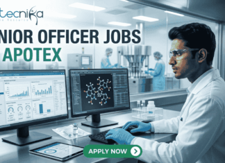 Apotex Hiring Junior Officers in Bangalore | Life Science Graduates Apply Now! Apotex Hiring Junior Officers in Bangalore Apply Now! A professional recruitment banner for "JUNIOR OFFICER JOBS AT APOTEX" featuring the Biotecnika logo at the top left. The image depicts a young male pharmaceutical professional in a white lab coat and blue gloves, meticulously monitoring data on dual computer screens. One screen displays analytical charts and graphs, while the other shows a 3D molecular structure. In the background, a sterile pharmaceutical production line with stainless steel machinery is visible through a large glass partition. On the right side, vertical teal icons highlight key roles: "QC QA," "Data Analysis," "Sterile Production," "Sterile vial," and "Ladder chart." A prominent green "APPLY NOW" button with a white arrow is centered at the bottom.