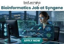 Bioinformatics Job at Syngene | Apply For Principal Scientist Role Today! Bioinformatics Job at Syngene Apply For Principal Scientist Role Today! A promotional banner for biotecnika advertising a "Bioinformatics Job at Syngene." The biotecnika logo is at the top center. The main image shows a woman with smart glasses working intensely at a high-tech computational workstation. A holographic overlay features detailed biological data visualizations, including DNA double-helices, molecular models, and complex data graphs. In the background, a whiteboard has the text "Genome Assembly Pipeline," and an urban night scene is visible through the window. At the bottom, a prominent green "APPLY NOW" button is centered.