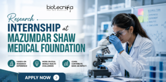 Research Internship at Mazumdar Shaw Medical Foundation. Research Internship at Mazumdar Shaw Medical Foundation banner featuring a scientist using a microscope in a modern lab, Biotecnika logo at the top, and an ‘Apply Now’ button highlighting hands-on research opportunities.