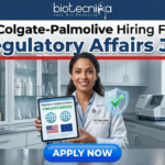 Colgate-Palmolive Hiring For Regulatory Affairs Job | BSc Life Science Job Colgate-Palmolive Hiring For Regulatory Affairs Job BSc Life Science Job. An image advertising a Regulatory Affairs job opening at Colgate-Palmolive, presented by Biotecnika. A smiling female regulatory specialist in a lab coat holds a tablet displaying a certified compliance status with US and EU flags and a green checkmark. A blue 'APPLY NOW' button is at the bottom.