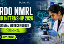 DRDO NMRL Paid Internship 2026 For M.Sc Biotechnology Students DRDO NMRL Paid Internship 2026 For MSc Biotechnology Students. Featured image showing a realistic biotechnology laboratory scene with a young female scientist using a microscope in a modern research lab. Bold text highlights “DRDO NMRL Paid Internship 2026 For MSc Biotechnology Students” with a bright neon-green and blue theme. The Biotecnika logo appears at the top center, while a large “Apply Now” button is placed prominently at the bottom. The design is vibrant, professional, and attention-grabbing, featuring biotech visuals such as DNA strands, lab equipment, and research elements to appeal to MSc Biotechnology students.